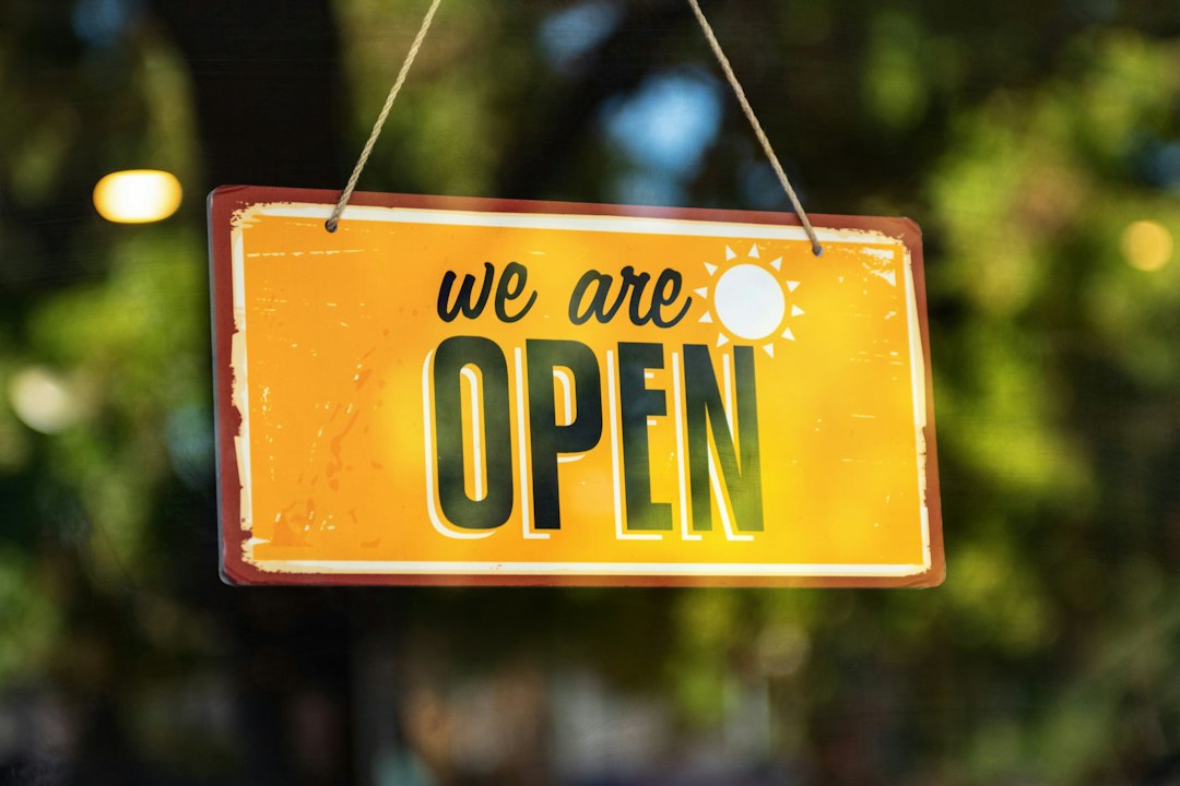 Cartel amarillo que dice we are open colgado en la vidriera de un local
